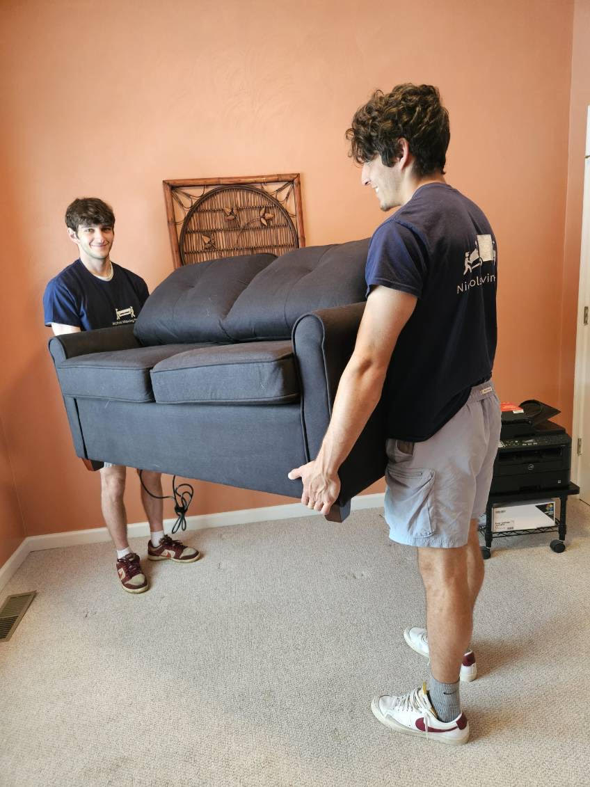 Two movers lifting a heavy couch onto the truck.